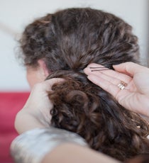Step 7: Gather loose hair to one side, twist a few pieces across the back of the head, and secure on the side with hairpins. 35_21_style2_step10