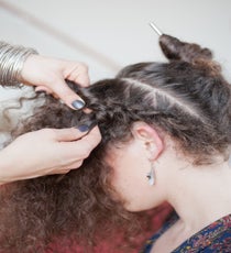 Step 2: Let the front section loose. Then, grab the hair on the right side of that section and secure it with a chopstick to get it out of the way. Begin French braiding the bottom section that sits below the diagonal part. 30_16_style2_step4-jpg