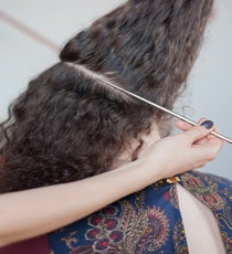 Step 1: Prep hair by smoothing a few drops of serum and a small dab of pomade throughout. On the right side of the head, starting behind the ear, go up and around the head, toward the crown, all the way to your left ear, and gather the hair in front in a headband-like motion. Section off this area. Then, starting at the left ear, take the remaining hair and begin to part diagonally across the back of the head, as shown. Combine the front section with the hair below the diagonal part in back. 29_15_style2_step1